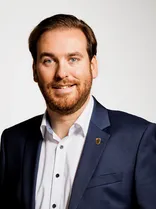 Andreas Sturm, Halbportrait, lächelnd, Blick in Kamera, neutraler Hintergrund