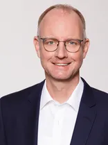 Timm Kern, formelles Halbporträt, lächelnd, Blick in Kamera, neutraler Hintergrund