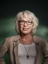 Martina Häußler, Halbportrait, lächelnd, Blick in Kamera, grüner Hintergrund