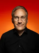 Sebastian Cuny, Halbportrait, lächelnd, Blick in Kamera, roter Hintergrund