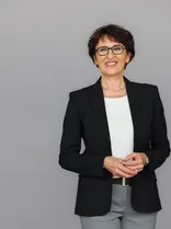 Ute Leidig, Halbportrait, lächelnd, Blick in Kamera, neutraler Hintergrund