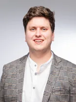 Finn Pfaller, formelles Porträt, lächelnd, Blick in Kamera, neutraler Hintergrund