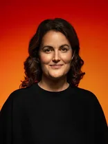 Anneke Graner, Halbportrait, lächelnd, Blick in Kamera, roter Hintergrund