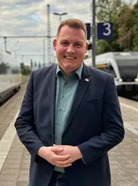 Niklas Nüssle, formelles Halbporträt, lächelnd, Blick in Kamera, draußen