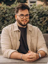 Simon Özkeles, Portrait, lächelnd, am Tisch sitzend