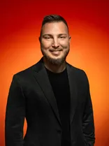 Jonas Aberle, Halbportrait, lächelnd, Blick in Kamera, roter Hintergrund