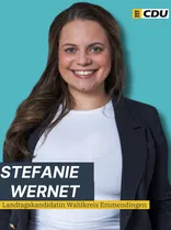 Stefanie Wernet, Halbportrait, lächelnd, Blick in Kamera, blauer Hintergrund