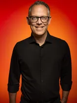 Peter Hutzel, Halbportrait, lächelnd, Blick in Kamera, roter Hintergrund