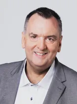 Ansgar Mayr, Halbportrait, lächelnd, Blick in Kamera, neutraler Hintergrund