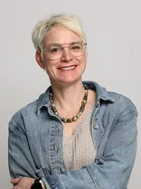 Hanna Binder, formelles Halbporträt, lächelnd, Blick in Kamera, neutraler Hintergrund