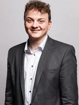 Luca Koengeter, formelles Halbporträt, lächelnd, Blick in Kamera, neutraler Hintergrund