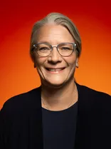 Martina Fuhrmann, Halbportrait, lächelnd, Blick in Kamera, roter Hintergrund