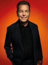 Klaus Ranger, Halbportrait, lächelnd, Blick in Kamera, roter Hintergrund