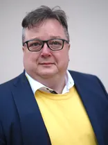 Jörg Breier, Halbportrait, lächelnd, Blick in Kamera, neutraler Hintergrund