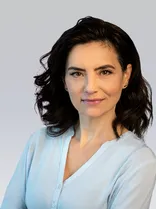 Meri Uhlig, Halbportrait, lächelnd, Blick in Kamera, neutraler Hintergrund