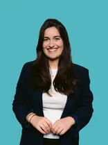 Teresa Schreiber, formelles Halbporträt, lächelnd, Blick in Kamera, blauer Hintergrund