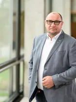 Klaus Hoher, formelles Halbporträt, Blick in Kamera, Hingrund im Bürogebäude