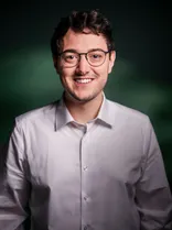 Mario Dietel, Halbportrait, lächelnd, Blick in Kamera, grüner Hintergrund