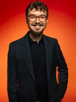 Michael Hofsäß, Halbportrait, lächelnd, Blick in Kamera, roter Hintergrund