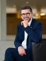 Niko Reith, Halbportrait, sitzend, lächelnd, Blick in Kamera