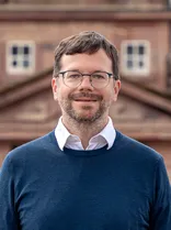 Florian Kollmann, Halbportrait, lächelnd, Blick in Kamera, draußen