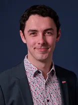 Adrian Keller, Halbportrait, lächelnd, Blick in Kamera, blauer Hintergrund