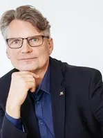 Thomas Hentschel, Halbportrait, lächelnd, Blick in Kamera, neutraler Hintergrund