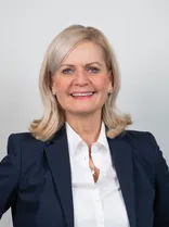 Kathrin Koelbl, Halbportrait, lächelnd, Blick in Kamera, neutraler Hintergrund