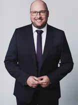 Carl Christian Hirsch, formelles Portrait, lächelnd, Blick in Kamera, grauer Hintergrund