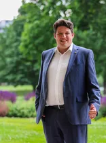 Michael Joukov, formelles Halbporträt, lächelnd, Blick in Kamera, draußen