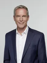 Jochen Haußmann, formelles Halbporträt, lächelnd, Blick in Kamera, neutraler Hintergrund