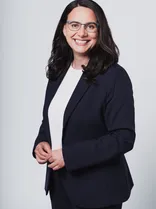 Katrin Schindele, Halbportrait, lächelnd, Blick in Kamera, grauer Hintergrund