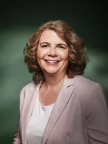 Nicole Heger, Halbportrait, lächelnd, Blick in Kamera, dunkelgrüner Hintergrund